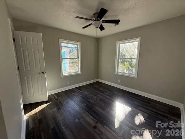 a view of empty room with wooden floor and fan
