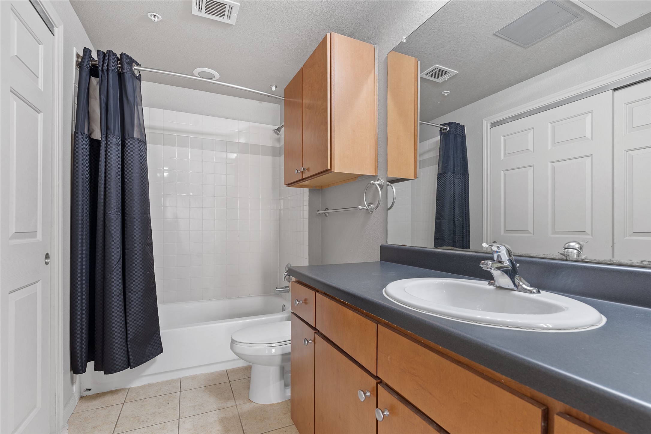 2515 Pearl Street, Unit 314 Austin, TX 78705 - Photo 2 of 17 Full bath with shower / bath combination with curtain, vanity, light tile patterned floors, and a textured ceiling