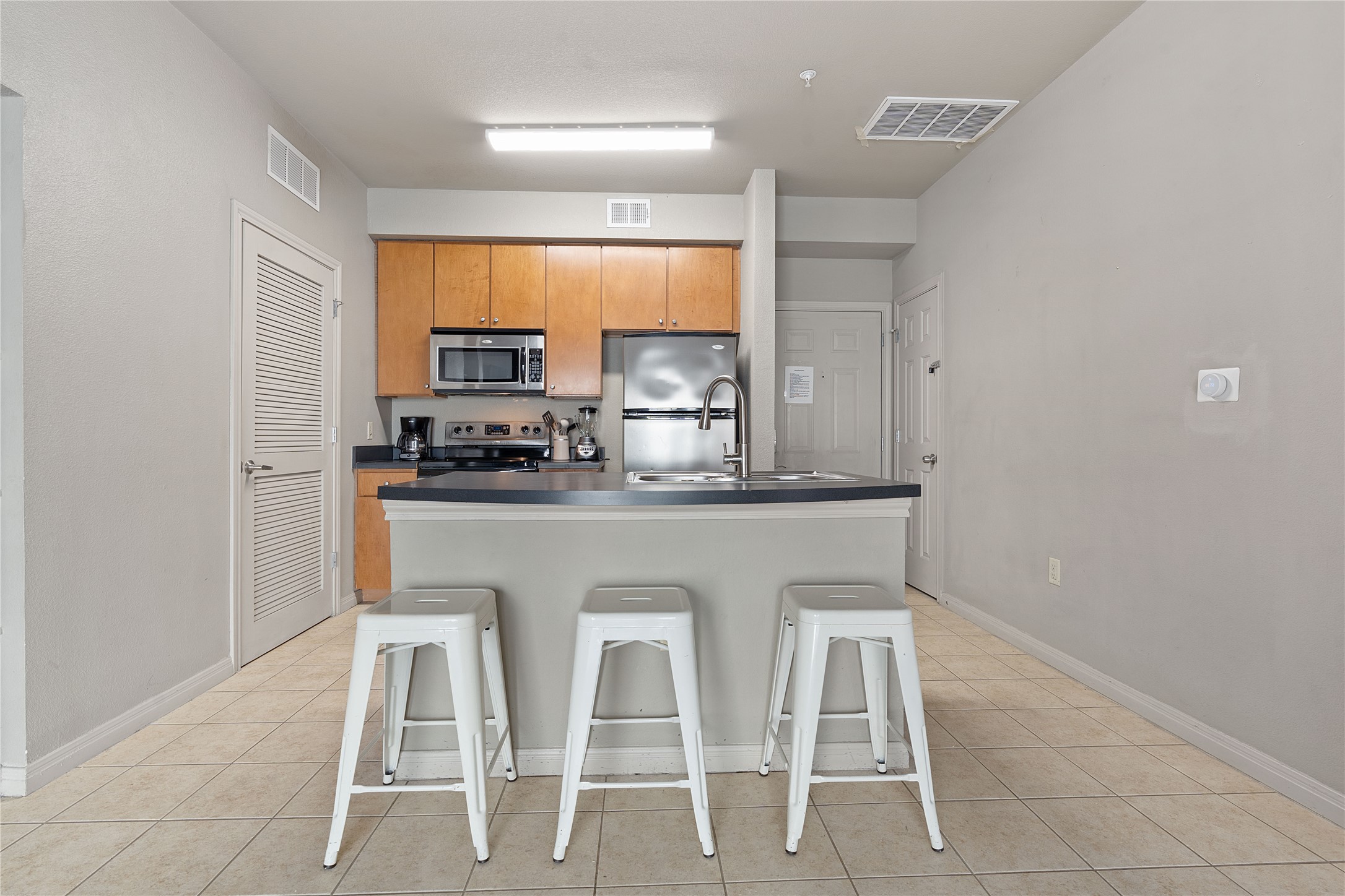 2515 Pearl Street, Unit 314 Austin, TX 78705 - Photo 8 of 17 Kitchen featuring light tile patterned floors, stainless steel appliances, a breakfast bar, and an island with sink