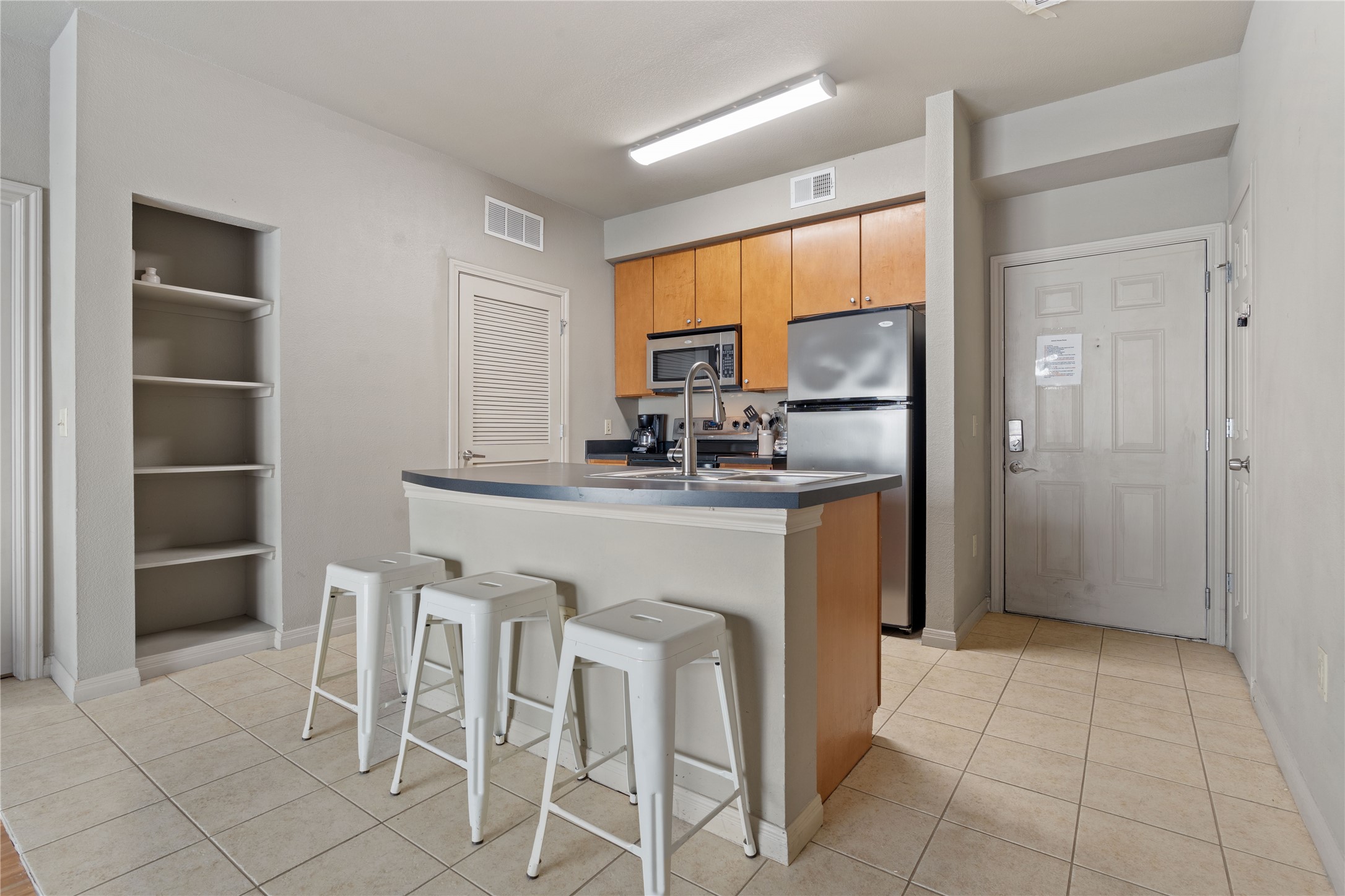 2515 Pearl Street, Unit 314 Austin, TX 78705 - Photo 9 of 17 Kitchen with appliances with stainless steel finishes, light tile patterned floors, a breakfast bar area, and a kitchen island with sink