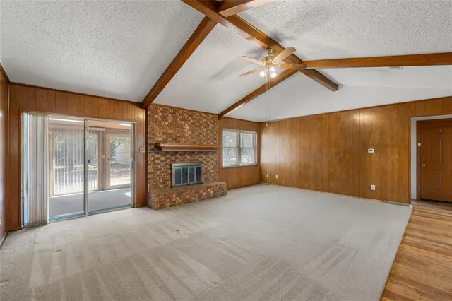 a view of an empty room with a fireplace and windows