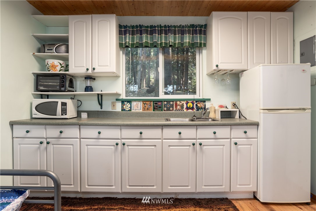 54 West Beach Path Olga, WA 98279 - Photo 22 of 39 a kitchen with white cabinets and white appliances