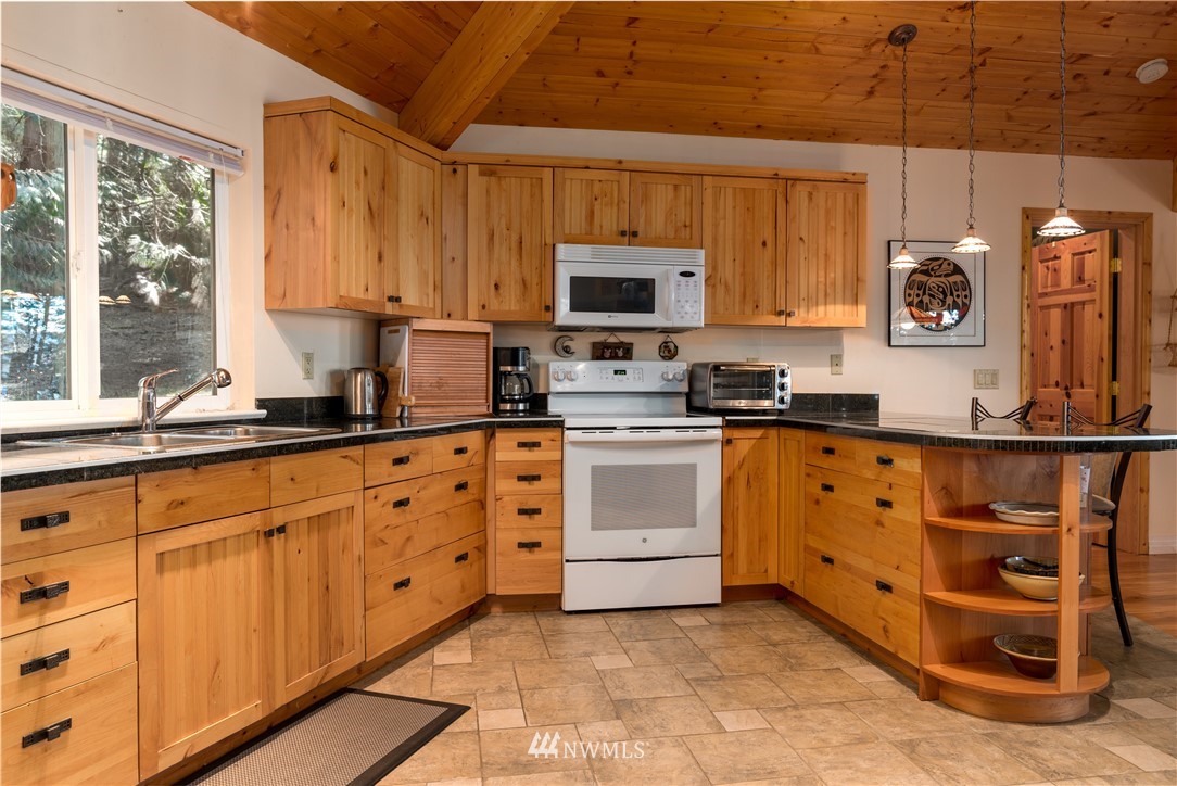 54 West Beach Path Olga, WA 98279 - Photo 3 of 39 a kitchen with granite countertop a sink window and cabinets