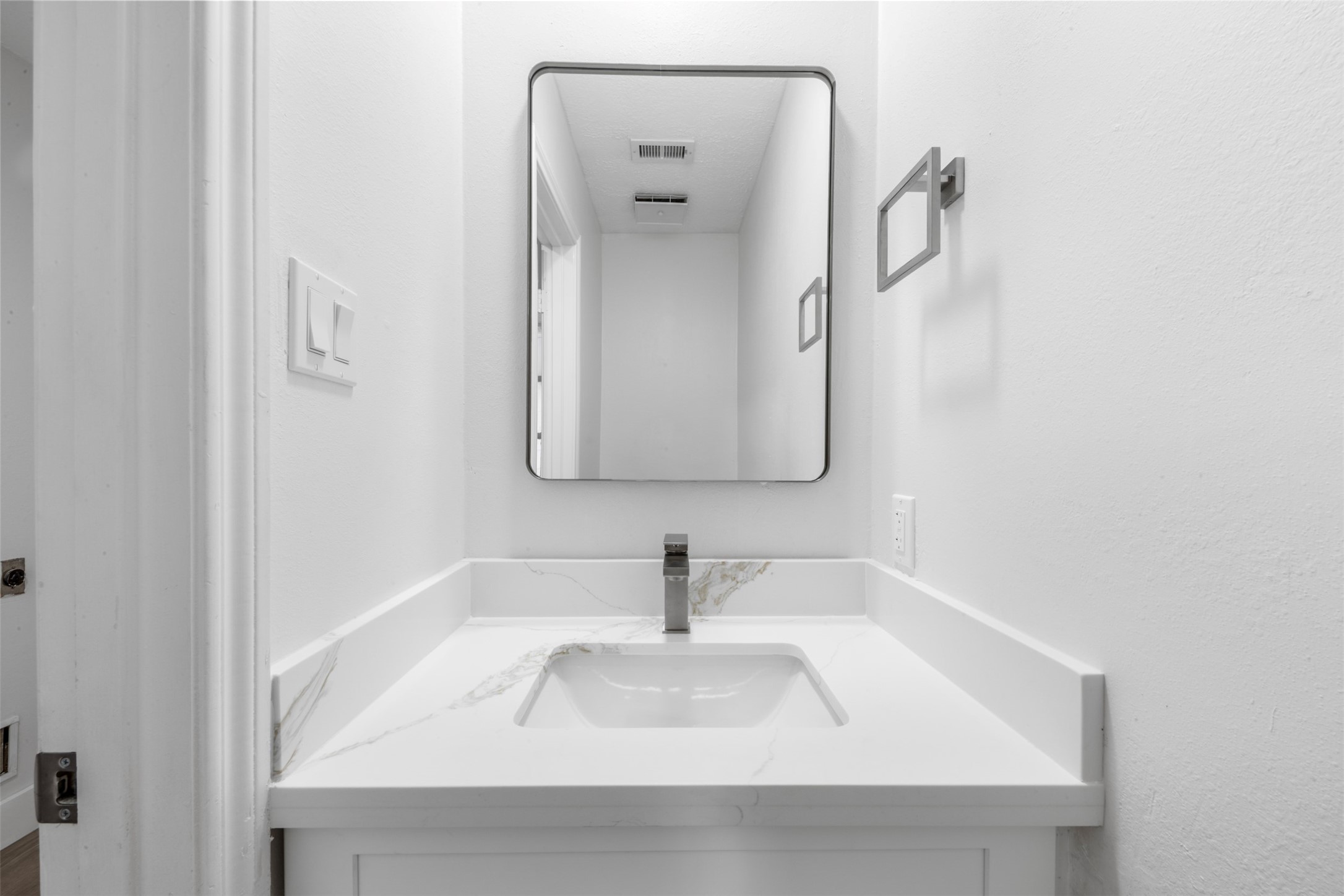 9543 Enstone Circle Spring, TX 77379 - Photo 34 of 50 This bathroom features a sleek, modern design with a white vanity and integrated sink. A large mirror adds depth, while minimalist fixtures and neutral tones provide a clean, contemporary look.