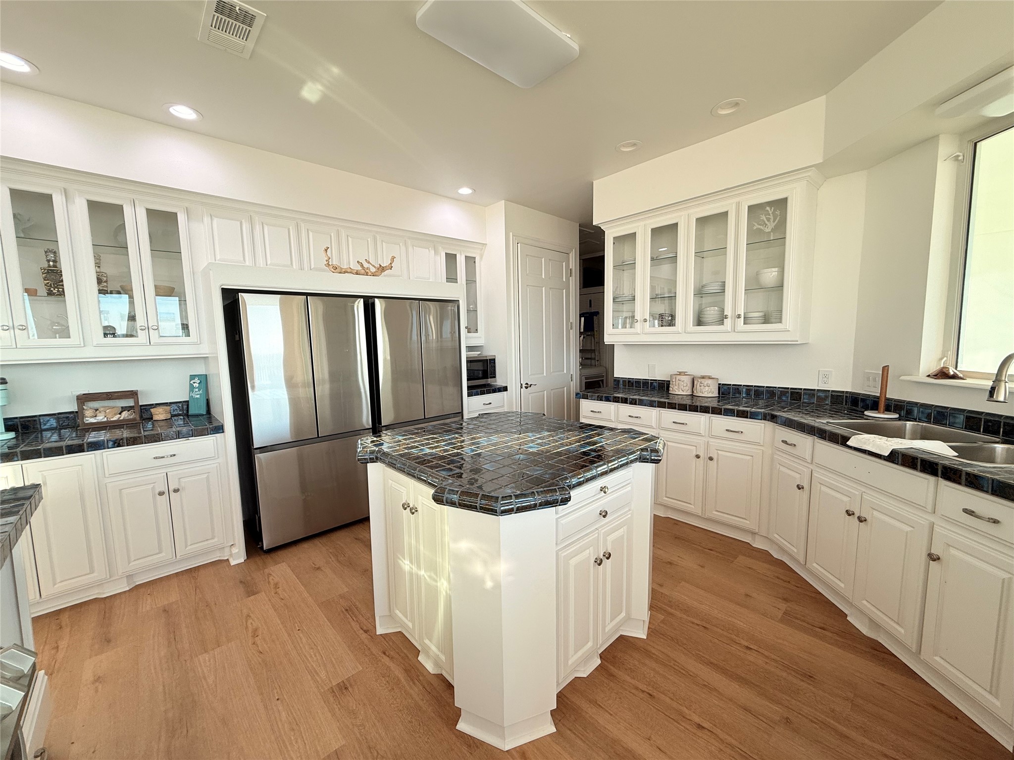 878 County Road 230 Sargent, TX 77414 - Photo 12 of 39 Bright, spacious kitchen with white cabinetry, a central island, stainless steel appliances, and tiled countertops.