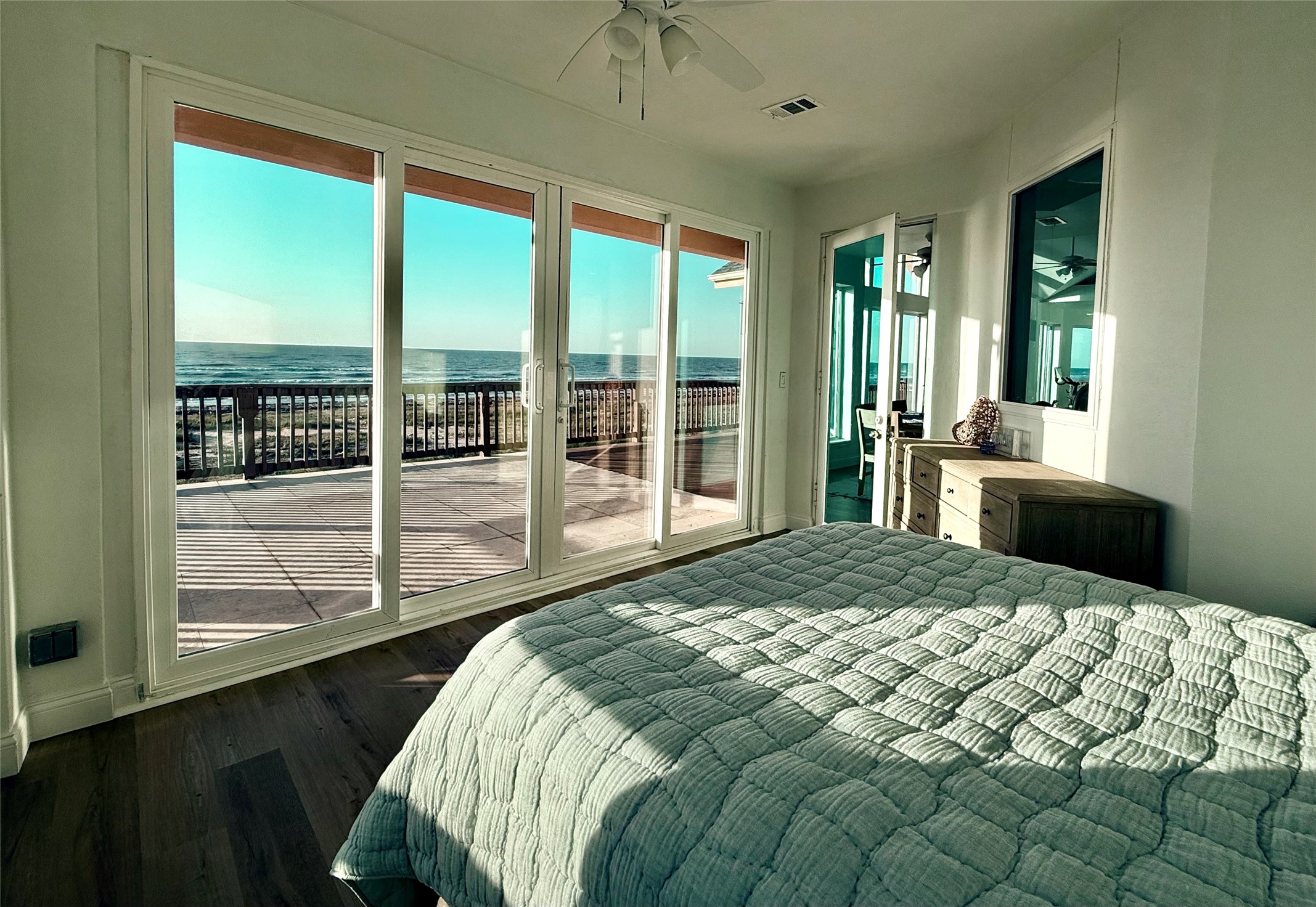 878 County Road 230 Sargent, TX 77414 - Photo 26 of 39 This spacious bedroom features large glass sliding doors that open to a private deck with stunning ocean views. The room is bright and airy creating a serene coastal retreat.