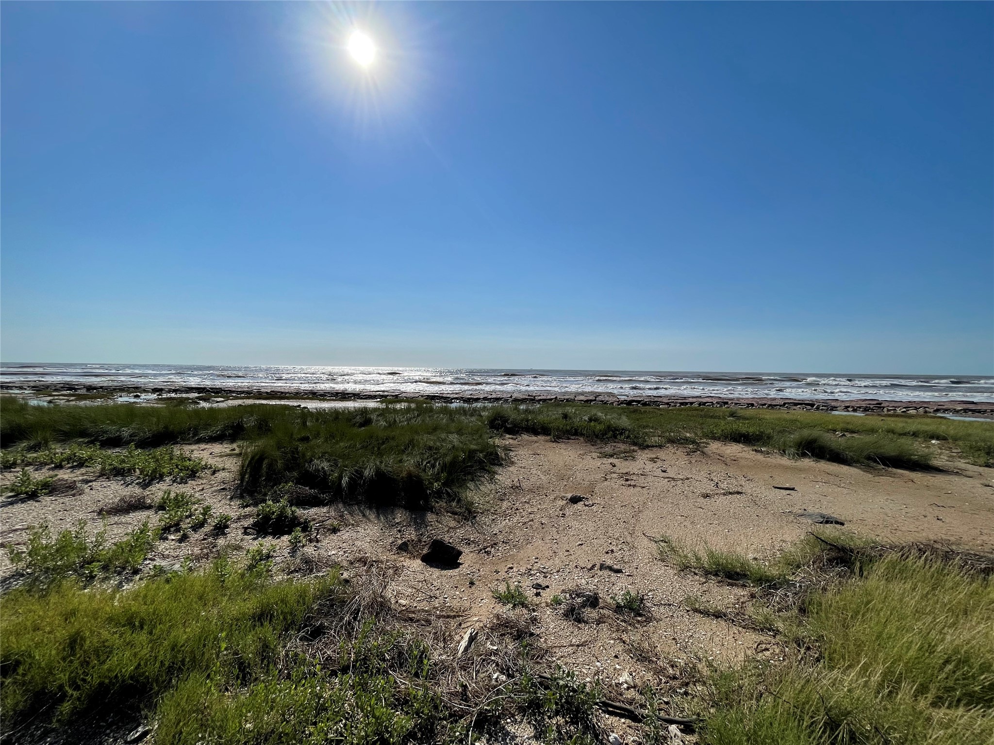 878 County Road 230 Sargent, TX 77414 - Photo 29 of 39 Expansive Gulf views, sandy shores, and lush greenery under a bright, clear sky. Ideal for those seeking a coastal lifestyle.