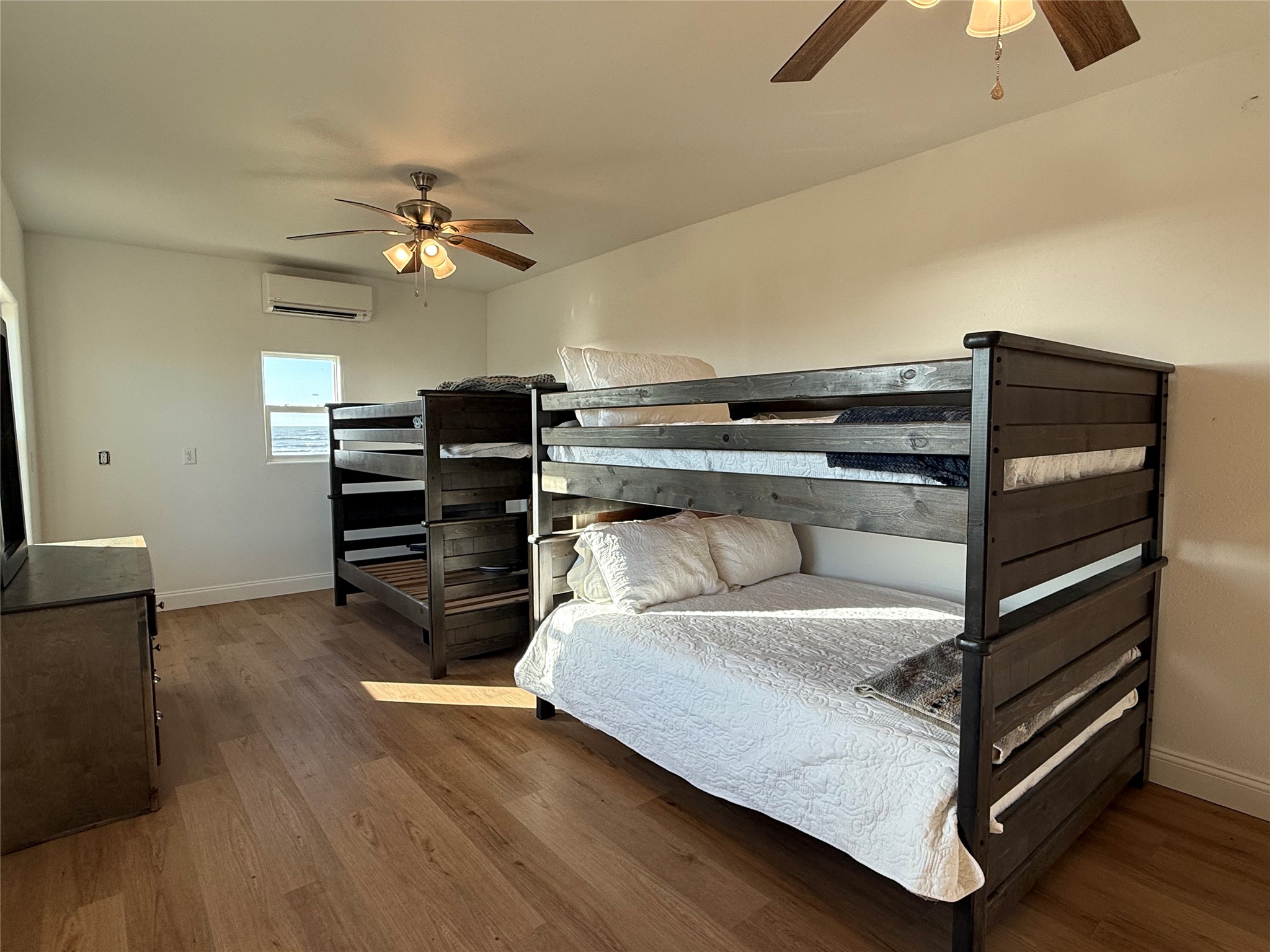 878 County Road 230 Sargent, TX 77414 - Photo 34 of 39 This spacious bedroom features two bunk beds, a ceiling fan, and Half bath, ideal for accommodating multiple guests comfortably.