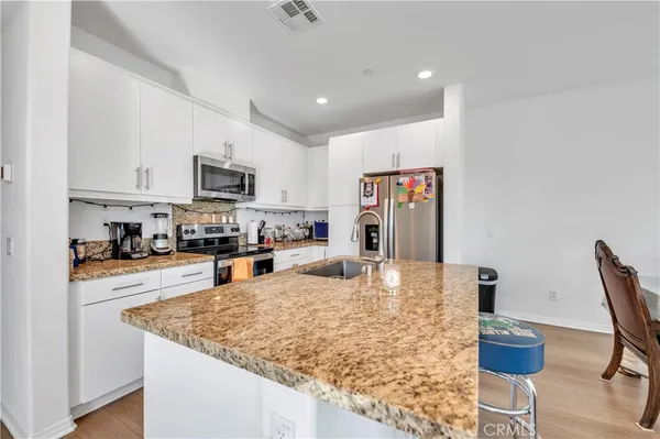 a kitchen with stainless steel appliances granite countertop a sink refrigerator and cabinets