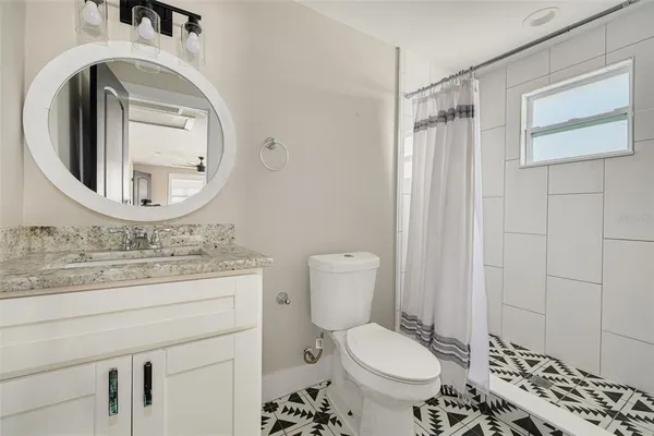 a bathroom with a granite countertop toilet sink and mirror