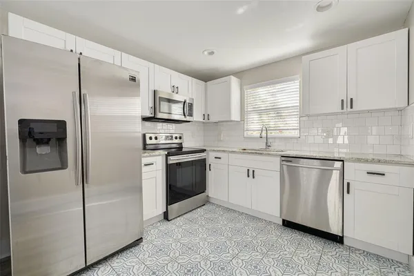 a kitchen with granite countertop white cabinets and stainless steel appliances