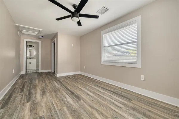 a view of empty room with wooden floor and fan