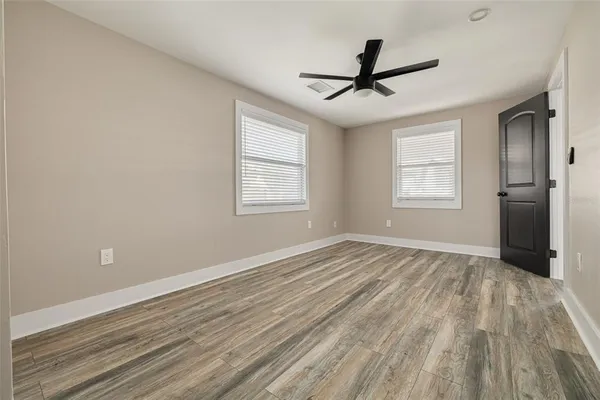 a view of empty room with wooden floor and fan