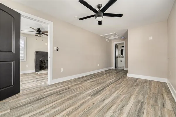 an empty room with wooden floor and a ceiling fan