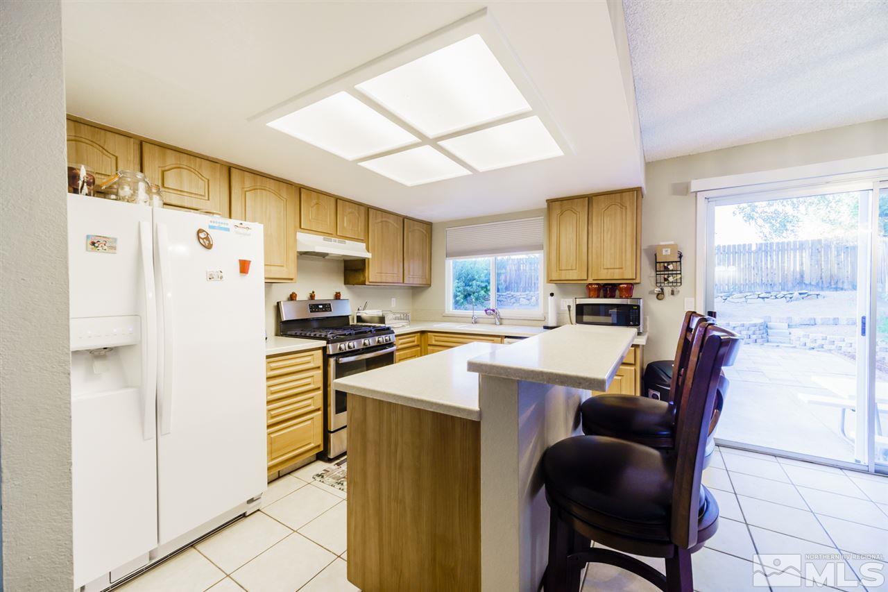 4275 Perro Lane Reno, NV 89502 - Photo 14 of 32 a kitchen with stainless steel appliances a refrigerator sink and wooden cabinets