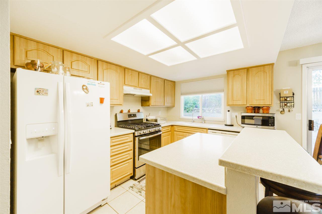 4275 Perro Lane Reno, NV 89502 - Photo 18 of 32 a kitchen with stainless steel appliances a refrigerator a stove a sink a dining table and chairs with wooden floor