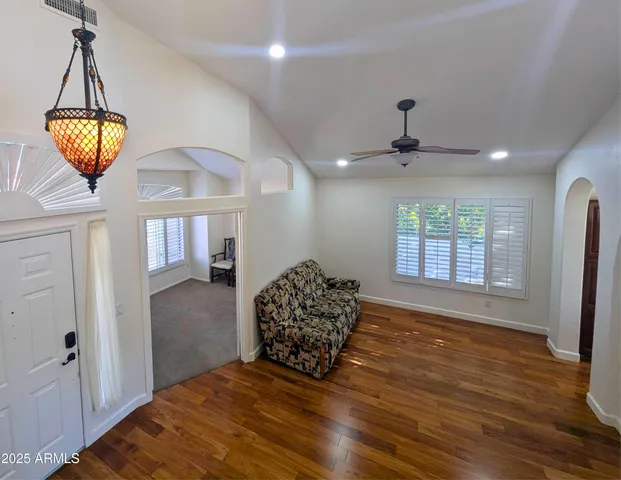 a view of a livingroom with wooden floor a ceiling fan and window