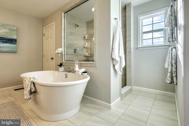 a white bath tub sitting in a bathroom and mirror