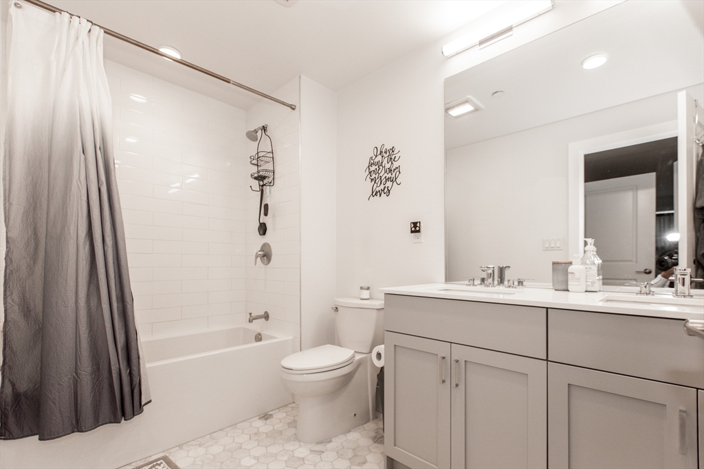 30 Polk Street, Unit 103 Boston, MA 02129 - Photo 10 of 20 a bathroom with a bathtub shower sink vanity and toilet
