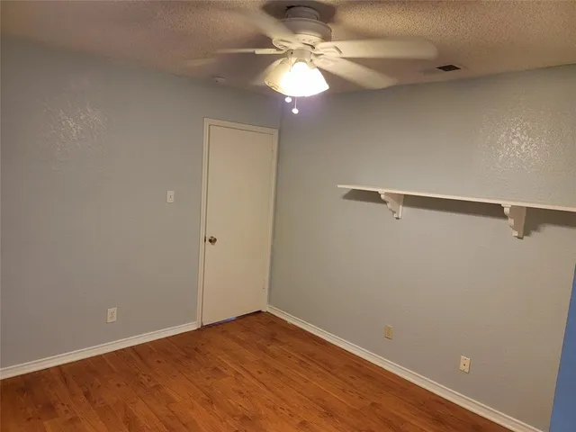 a view of a room with wooden floor and fan