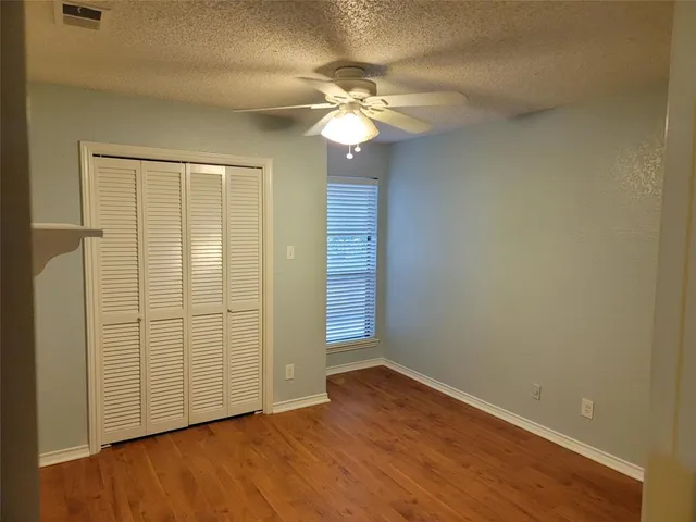 an empty room with wooden floor and fan