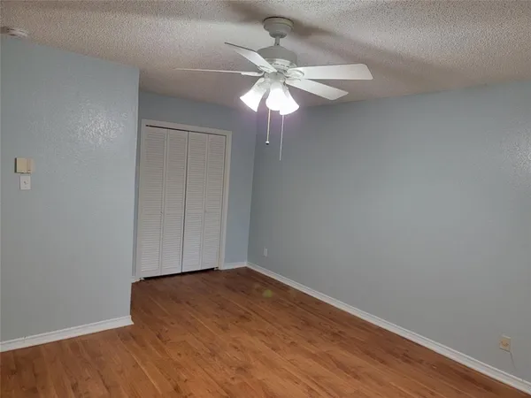 a view of a small space with wooden floor and a fan