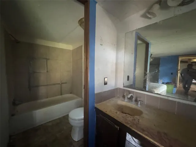 a bathroom with a granite countertop sink a toilet and shower
