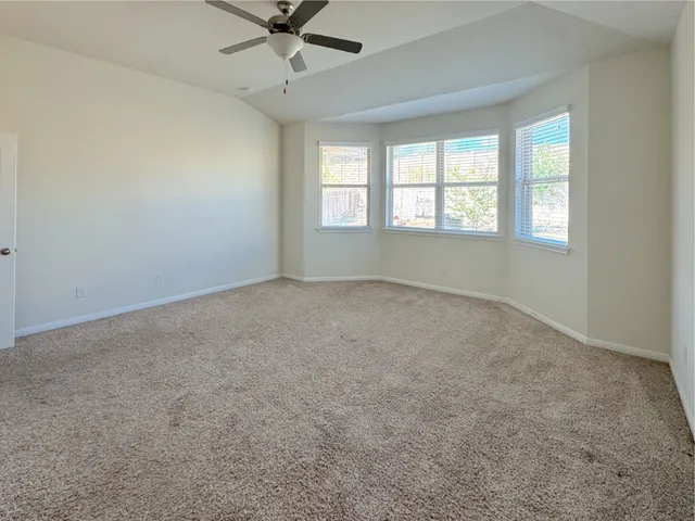 an empty room with a window and a fan