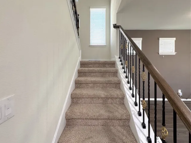 a view of staircase with lots of frames on wall and wooden floor