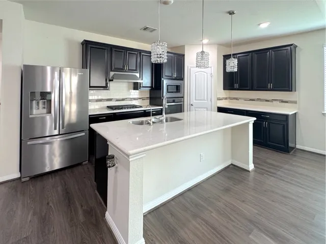 a kitchen with stainless steel appliances a refrigerator and a stove top oven