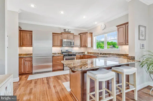 a kitchen with stainless steel appliances a stove a sink dishwasher and a refrigerator with wooden floor
