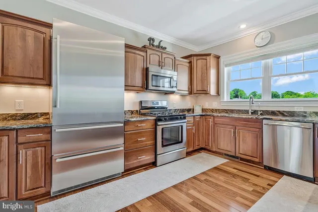a kitchen with stainless steel appliances kitchen island granite countertop a refrigerator and a stove top oven