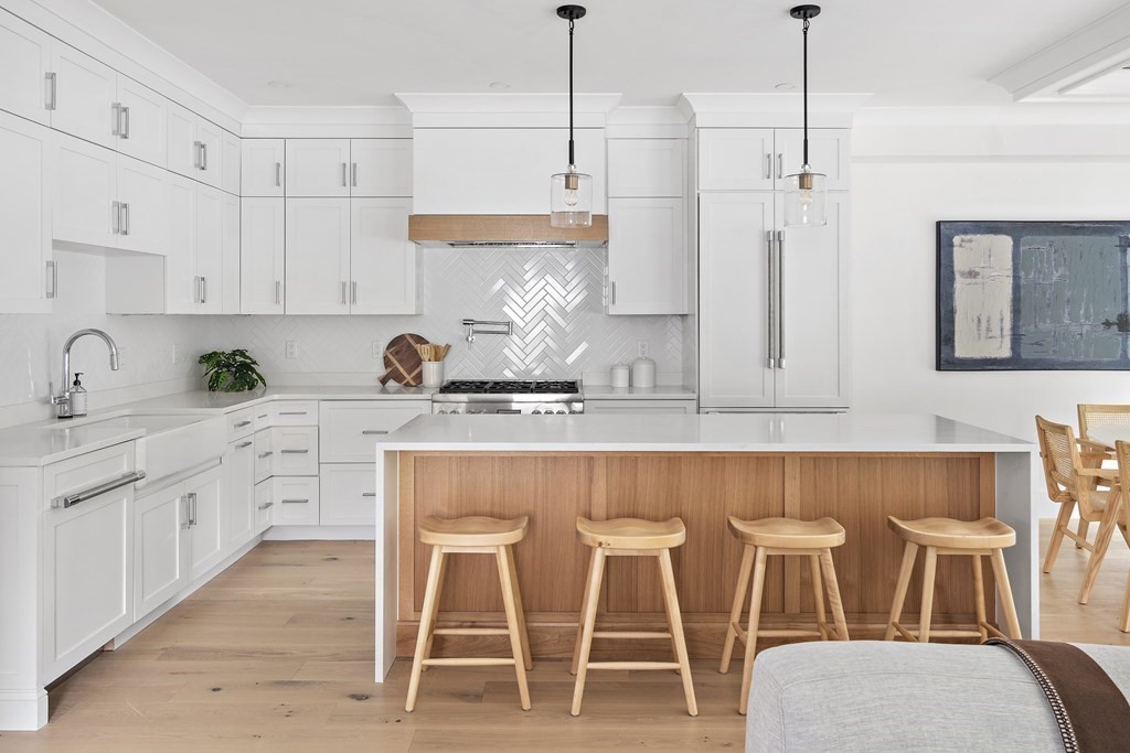 a kitchen with white cabinets and chairs
