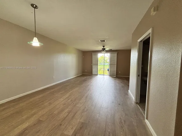 a view of an empty room with window and wooden floor