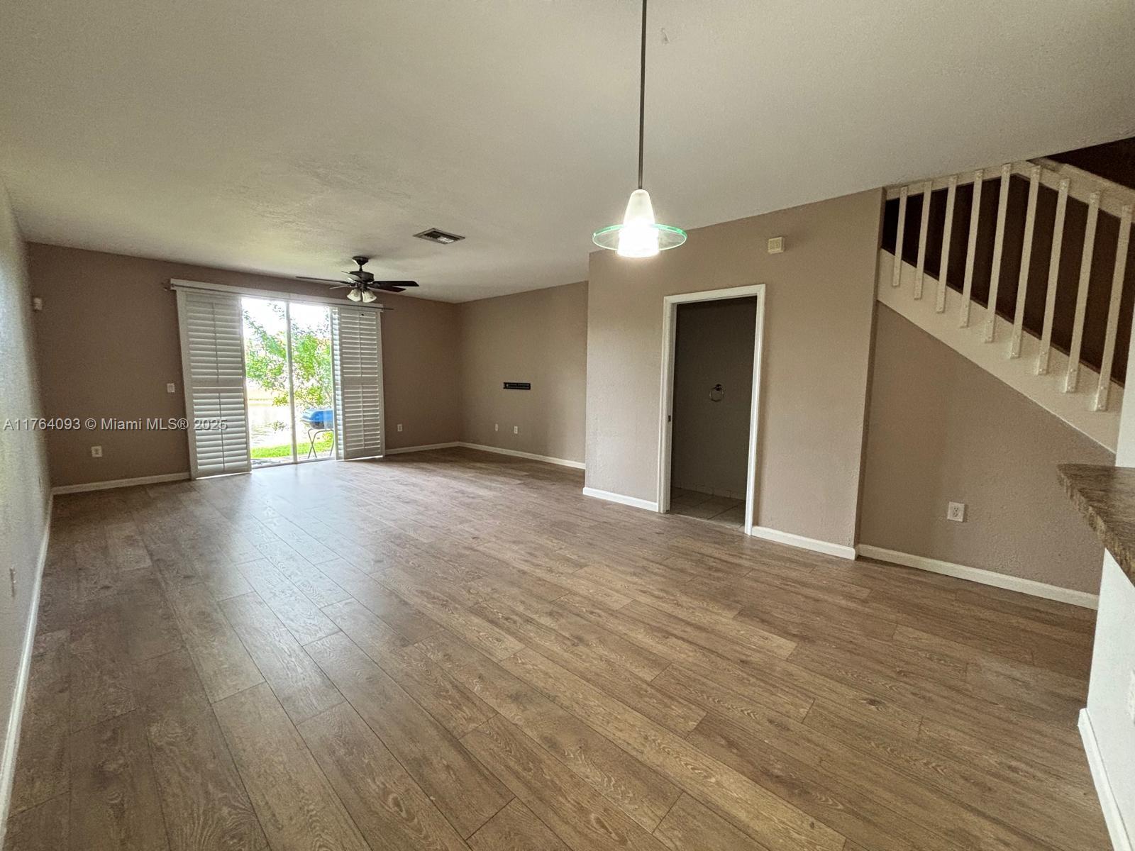 8253 Southwest 29th Street, Unit 104 Miramar, FL 33025 - Photo 5 of 17 a view of an empty room with wooden floor and windows
