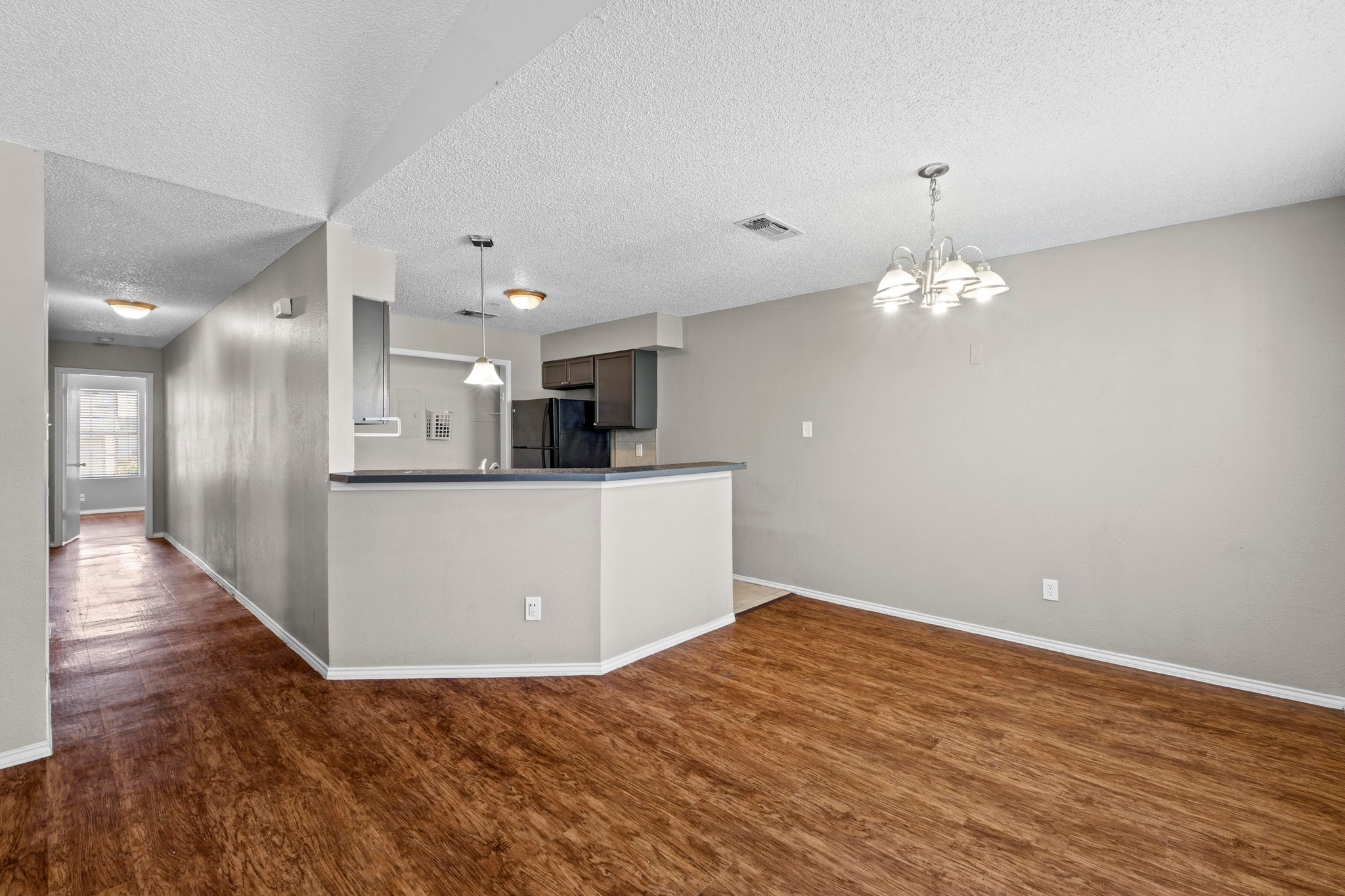 4208 Duval Road, Unit C Austin, TX 78759 - Photo 5 of 28 Kitchen with wood finished floors, a textured ceiling, dark countertops, a chandelier, and freestanding refrigerator