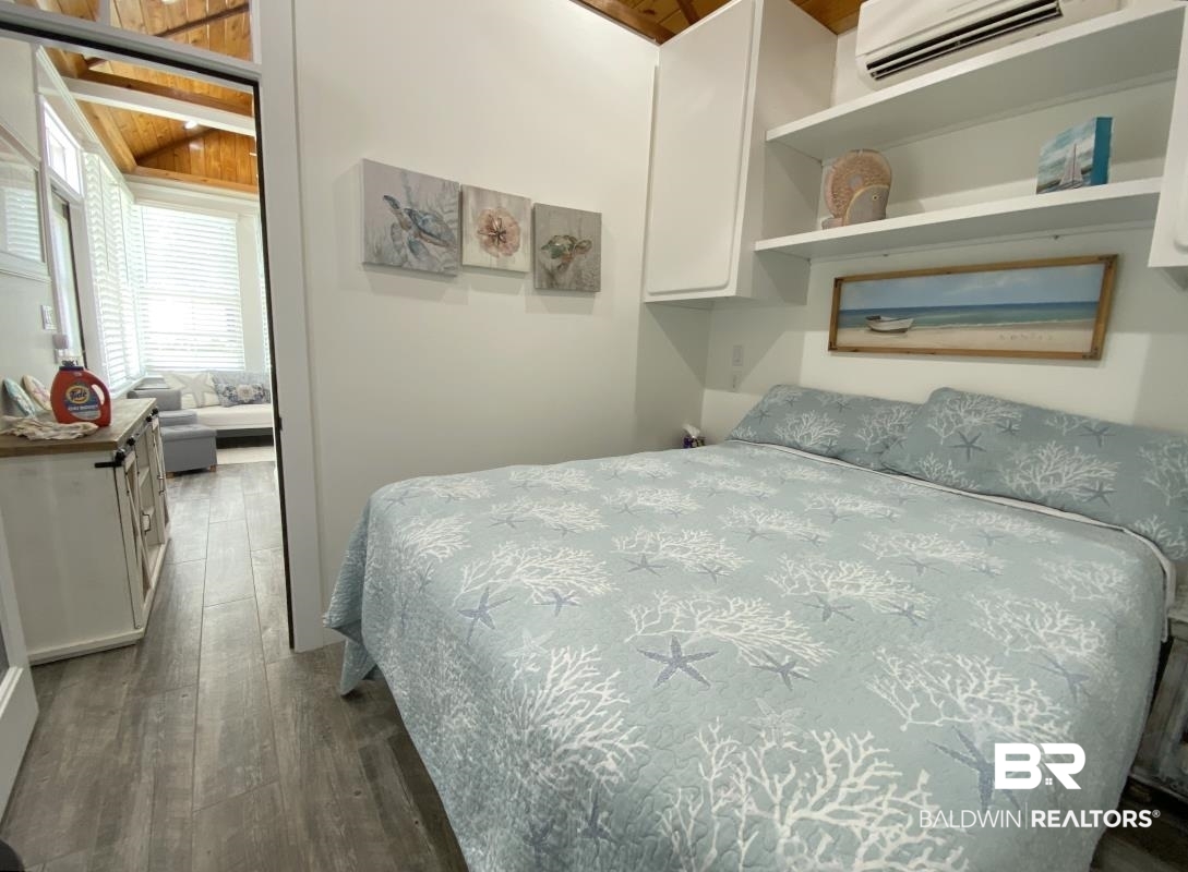 28888 Canal Road, Unit 77 Orange Beach, AL 36561 - Photo 10 of 23 Wood-finish flooring throughout, built-in shelving, white cabinetry, a vaulted wood-paneled ceiling, and an integrated air conditioning unit