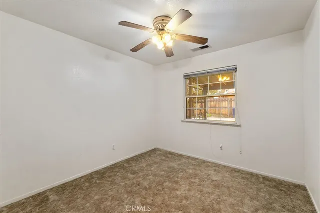 an empty room with closet and a chandelier fan