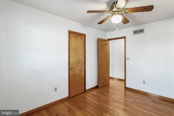 an empty room with wooden floor closet and fan