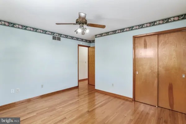 a view of empty room with wooden floor and fan