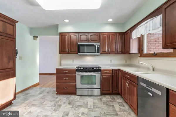 a kitchen with stainless steel appliances granite countertop wooden cabinets a stove top oven a sink and dishwasher