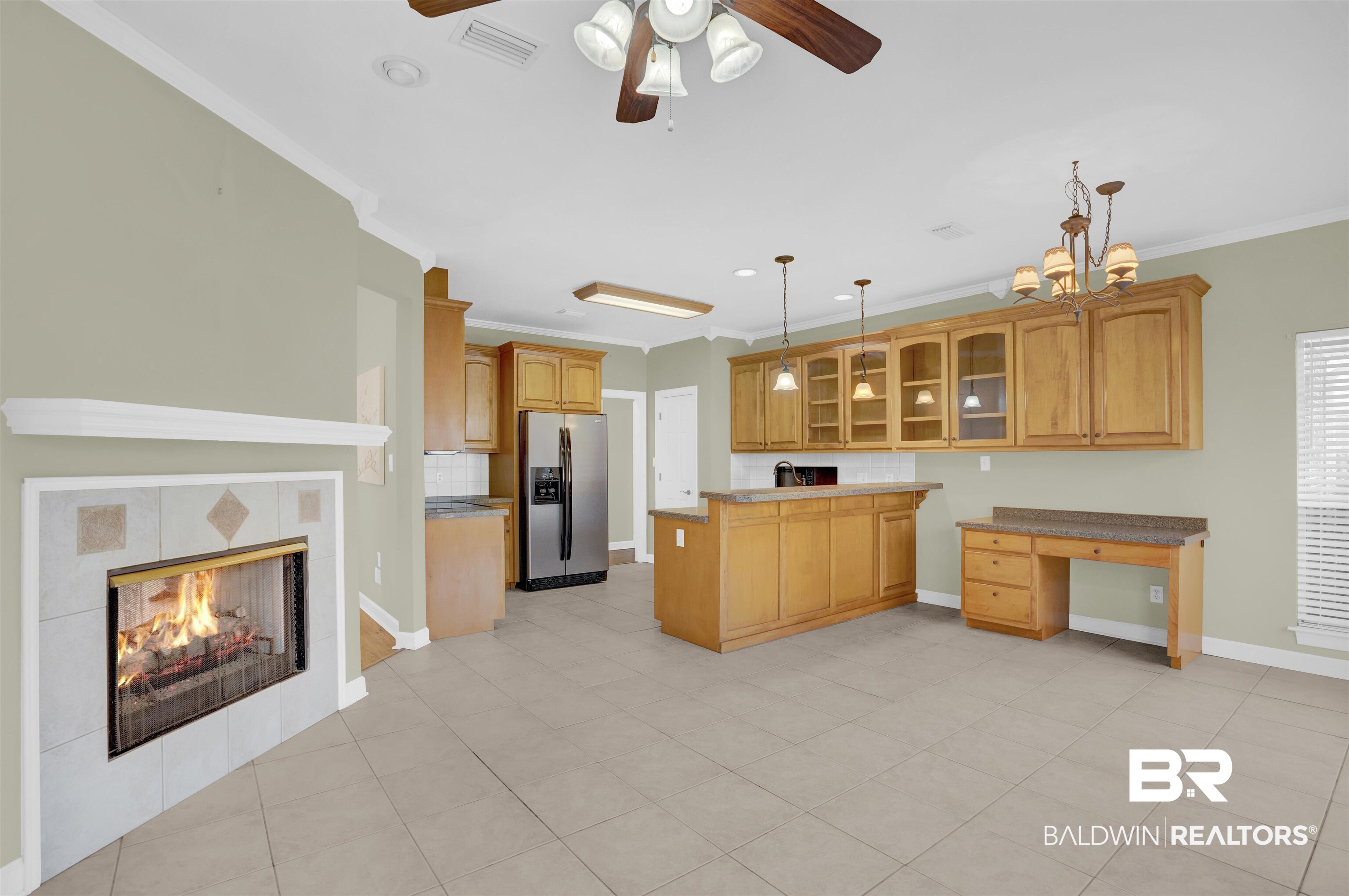 100 Conti Court Fairhope, AL 36532 - Photo 25 of 54 Kitchen with ceiling fan with notable chandelier, crown molding, stainless steel fridge with ice dispenser, hanging light fixtures, and a tiled fireplace