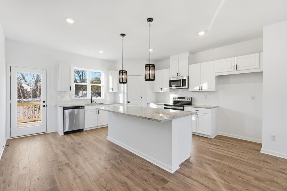 5708 Schelton Place Southeast Mableton, GA 30126 - Photo 7 of 48 a kitchen with stainless steel appliances white cabinets a sink a stove a kitchen island and hard wood floors