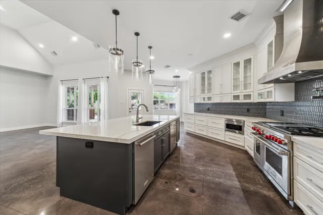 a kitchen with stainless steel appliances granite countertop a sink a stove and a wooden floors