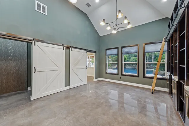 an empty room with chandelier fan and windows