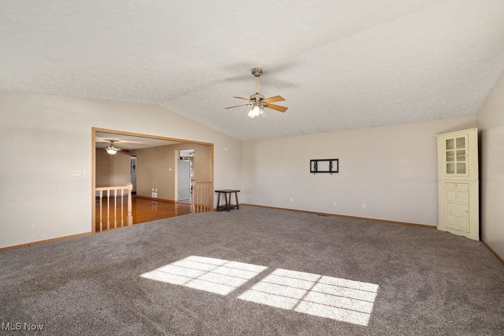 Unfurnished room featuring carpet floors, ceiling fan, and lofted ceiling