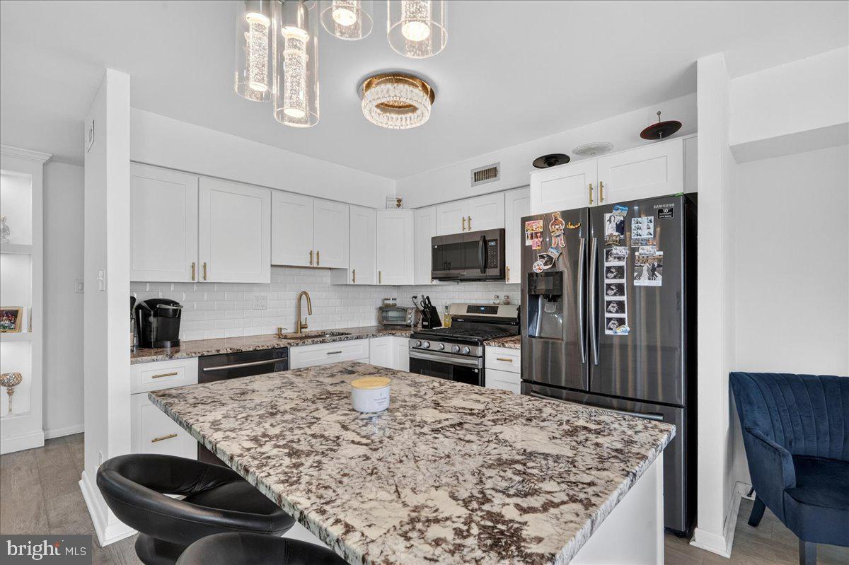 8930 Krewstown Road, Unit 310 Philadelphia, PA 19115 - Photo 7 of 32 a kitchen with stainless steel appliances granite countertop a sink dishwasher stove refrigerator and microwave with wooden floor