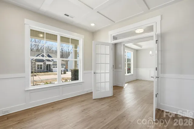 an empty room with wooden floor and windows