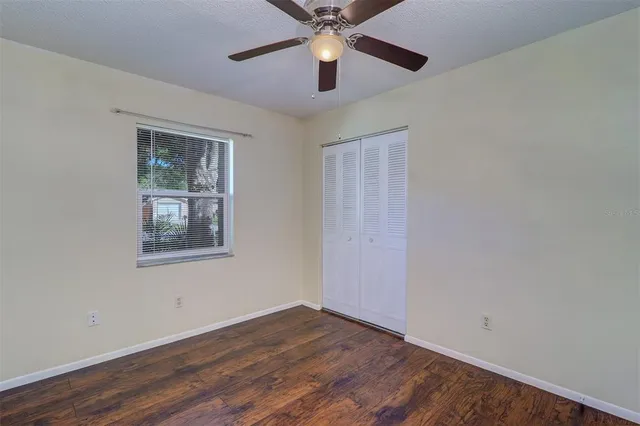 a view of an empty room with window and a chandelier fan