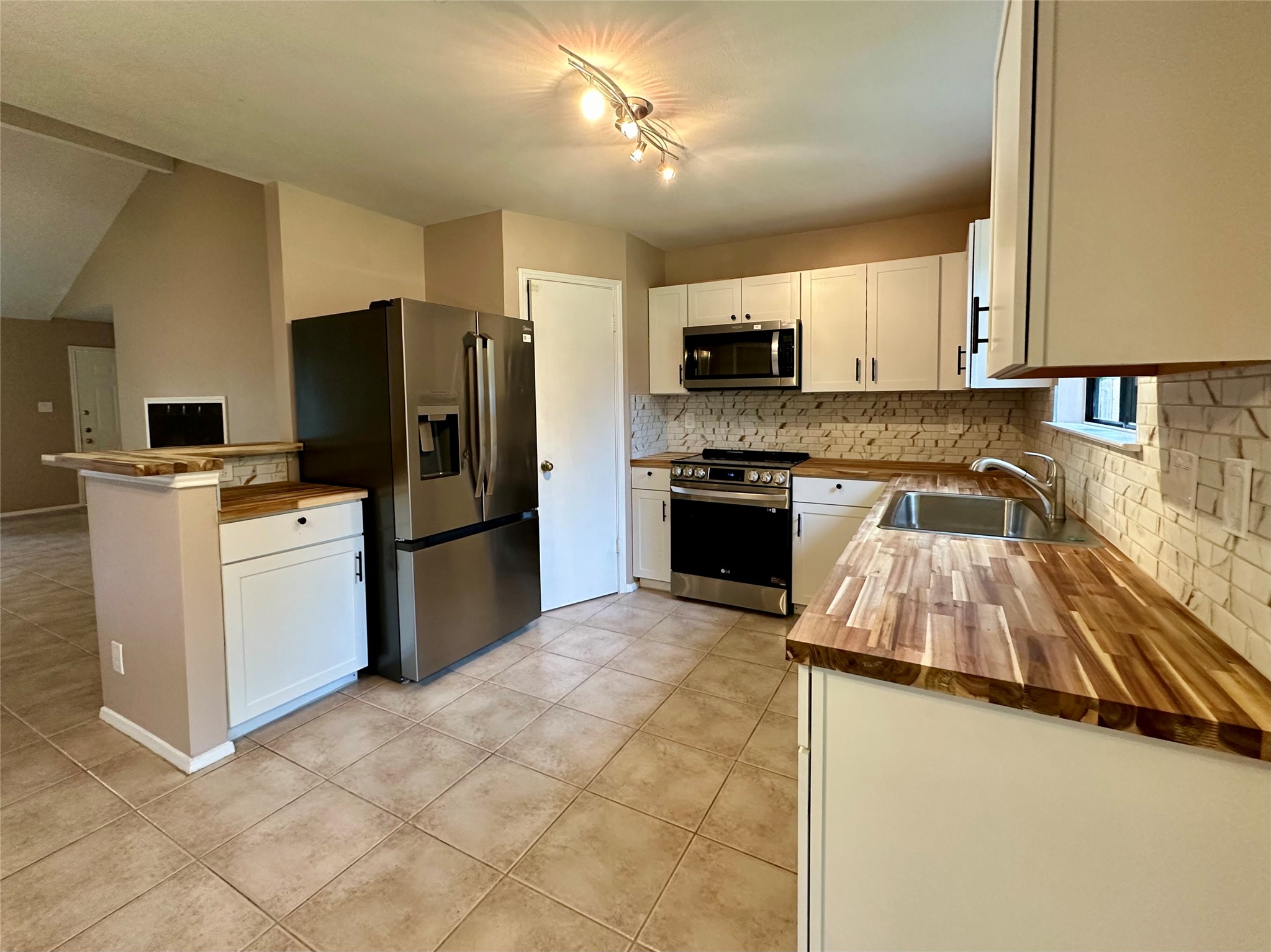 709 Brookside Pass Cedar Park, TX 78613 - Photo 2 of 10 The kitchen features white cabinetry, wood countertops, stainless steel appliances, and a tiled backsplash